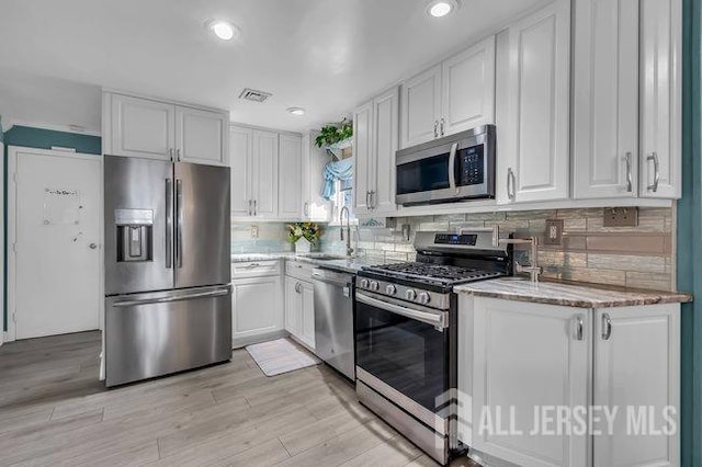 kitchen featuring sink, appliances with stainless steel finishes, white cabinets, and decorative backsplash