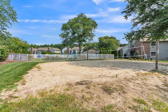 view of yard featuring volleyball court, fence, and a residential view