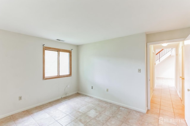 spare room with stairway, baseboards, light tile patterned floors, and visible vents