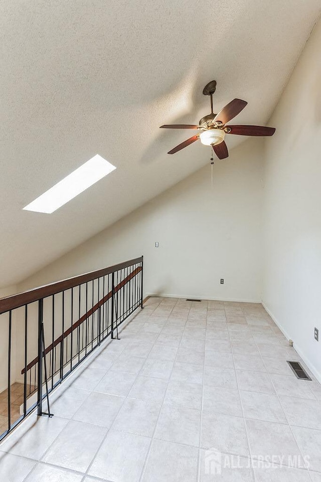 bonus room with lofted ceiling with skylight, visible vents, a textured ceiling, and a ceiling fan