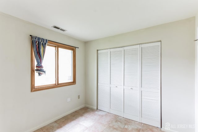 unfurnished bedroom featuring baseboards, visible vents, and a closet