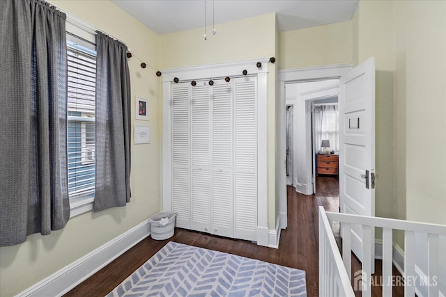 bedroom with baseboards, wood finished floors, and a closet