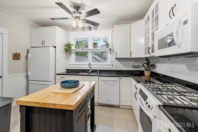 kitchen with white appliances, a sink, light tile patterned floors, decorative backsplash, and white cabinets