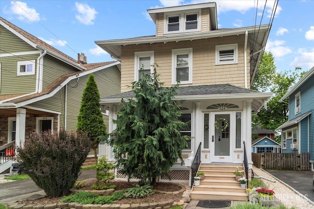 traditional style home featuring roof with shingles and fence