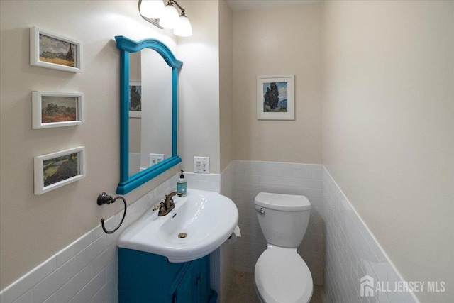 bathroom featuring tile walls, a wainscoted wall, toilet, and vanity