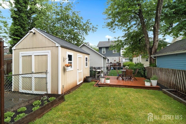 view of yard with a shed, a wooden deck, an outbuilding, outdoor dining area, and a garden