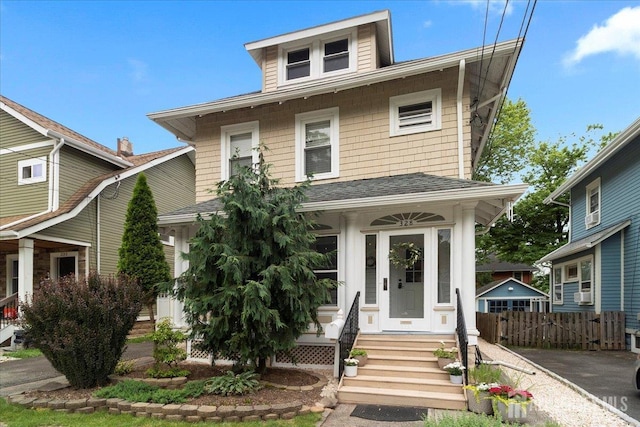 american foursquare style home with a shingled roof and fence