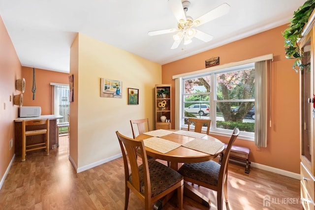 dining room featuring light wood finished floors, baseboards, and a ceiling fan
