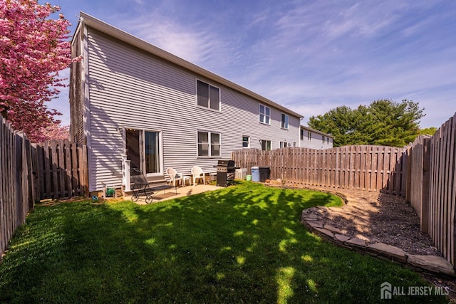 back of property with a fenced backyard, a patio, and a lawn