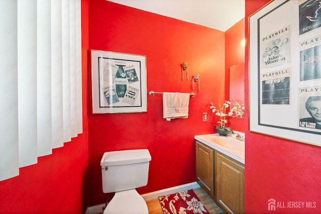 half bath with vanity, toilet, and baseboards