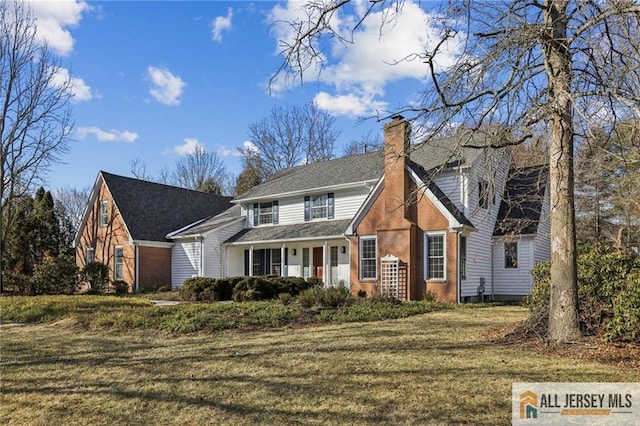 view of front of home featuring a chimney, a front lawn, and brick siding