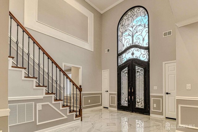 foyer featuring french doors, ornamental molding, and a high ceiling