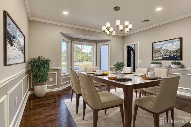 dining room featuring dark hardwood / wood-style floors, an inviting chandelier, and ornamental molding