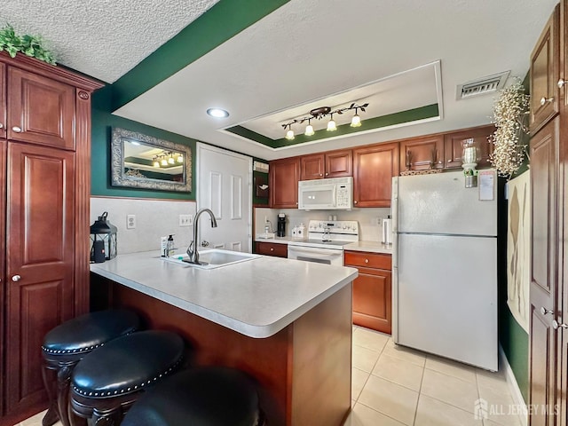 kitchen featuring a sink, a peninsula, white appliances, visible vents, and light tile patterned floors