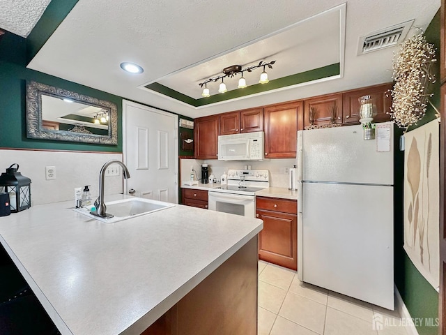 kitchen with a peninsula, a sink, visible vents, white appliances, and light countertops
