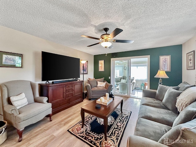 living area with a ceiling fan, light wood finished floors, and a textured ceiling