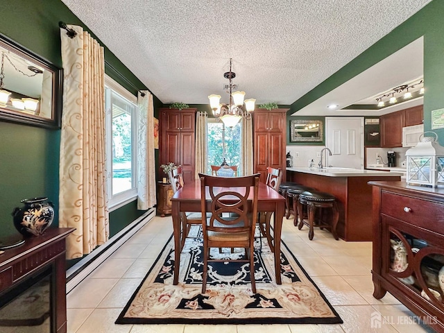 dining room with a notable chandelier, a textured ceiling, a baseboard heating unit, light tile patterned floors, and track lighting