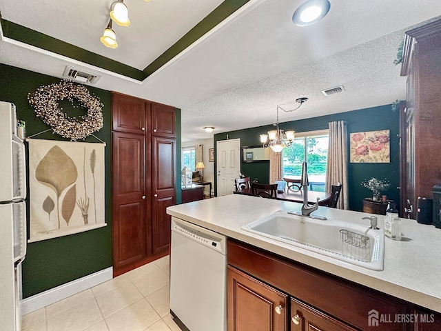 kitchen featuring white dishwasher, hanging light fixtures, an inviting chandelier, visible vents, and a sink