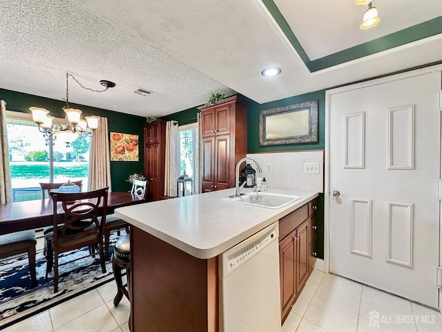 kitchen with a sink, visible vents, light tile patterned floors, white dishwasher, and a notable chandelier