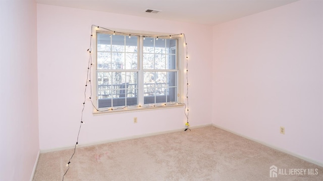 carpeted spare room featuring visible vents and baseboards