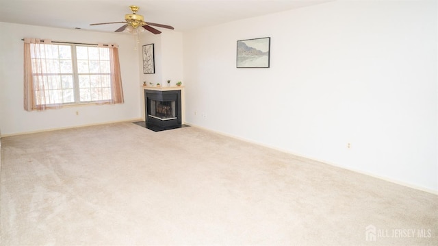 unfurnished living room with carpet floors, ceiling fan, and a fireplace with flush hearth