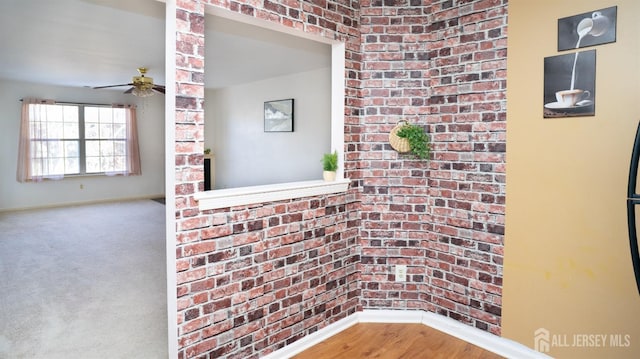 interior space featuring baseboards, brick wall, and wood finished floors