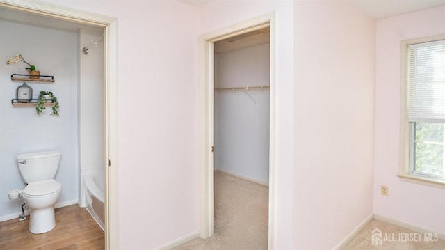 full bathroom featuring a wealth of natural light, baseboards, and toilet