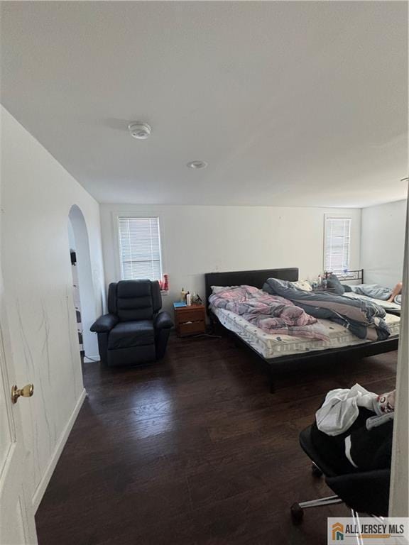 bedroom featuring arched walkways and wood finished floors