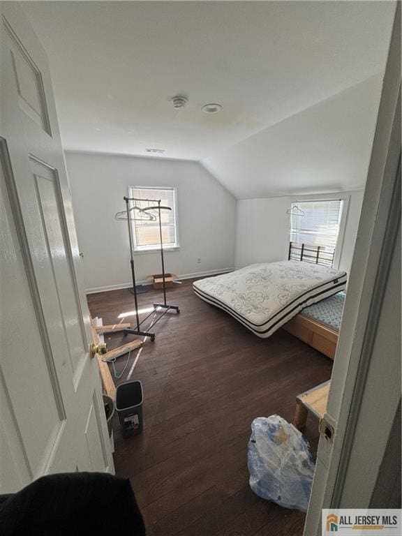 bedroom with baseboards, vaulted ceiling, and wood finished floors