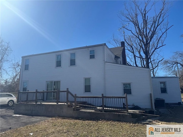 back of property featuring central AC and a chimney