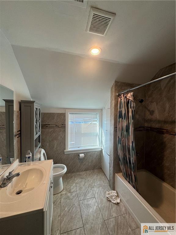 full bathroom featuring visible vents, toilet, vaulted ceiling, shower / bath combination with curtain, and vanity