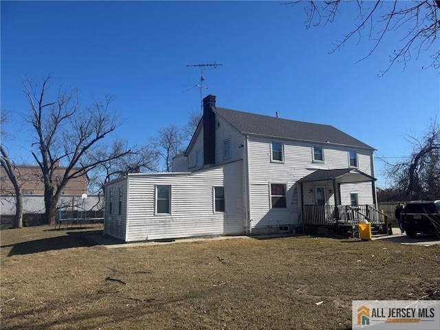 rear view of house featuring a trampoline, a yard, and a chimney