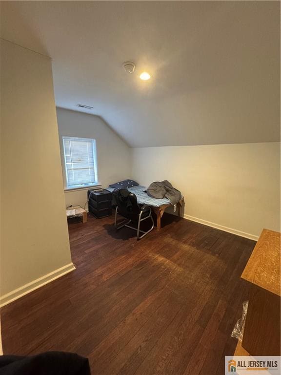 interior space featuring lofted ceiling, dark wood-style floors, visible vents, and baseboards