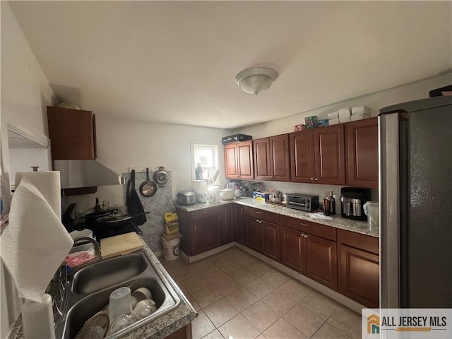 kitchen featuring a toaster, light countertops, a sink, and light tile patterned floors