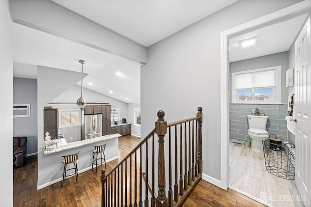 corridor with a wealth of natural light, an upstairs landing, and wood finished floors