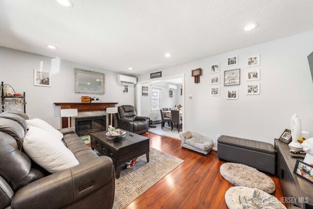 living area with dark wood-type flooring, recessed lighting, a wall unit AC, and a fireplace