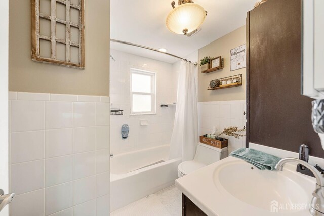 full bathroom featuring toilet, visible vents, vanity, tile walls, and shower / bath combo