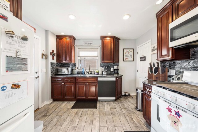 kitchen with light wood finished floors, tasteful backsplash, recessed lighting, a sink, and white appliances