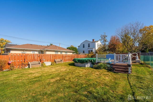 view of yard with a fenced in pool, a fenced backyard, and a wooden deck