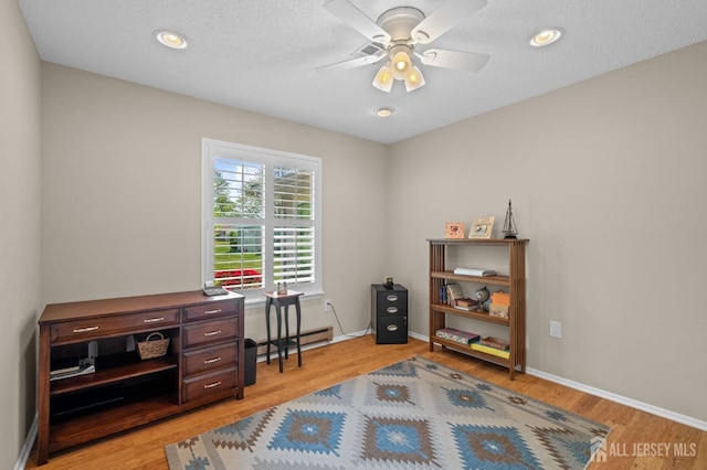 home office with light wood finished floors, ceiling fan, baseboard heating, and baseboards