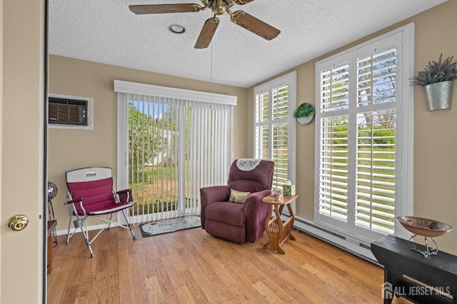 living area with a textured ceiling, wood finished floors, a ceiling fan, and a baseboard radiator