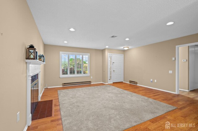 unfurnished living room featuring a baseboard radiator, light wood-style flooring, baseboards, and recessed lighting
