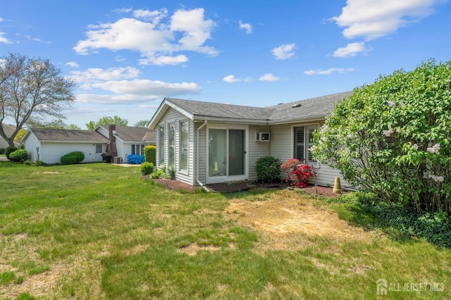 rear view of property featuring a lawn and a shingled roof