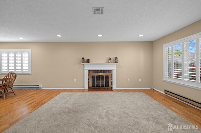 unfurnished living room with wood finished floors, a fireplace, recessed lighting, a baseboard heating unit, and a textured ceiling