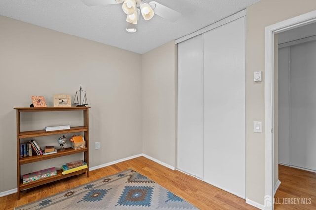 miscellaneous room featuring wood finished floors, a ceiling fan, and baseboards