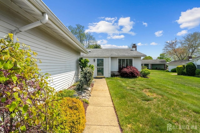 view of exterior entry featuring a yard and a chimney
