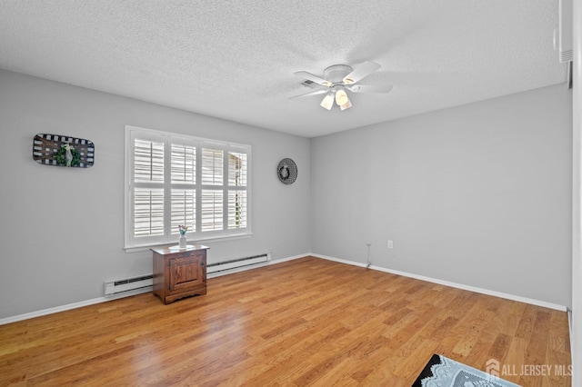 spare room featuring baseboard heating, ceiling fan, light wood-style flooring, a textured ceiling, and a baseboard heating unit
