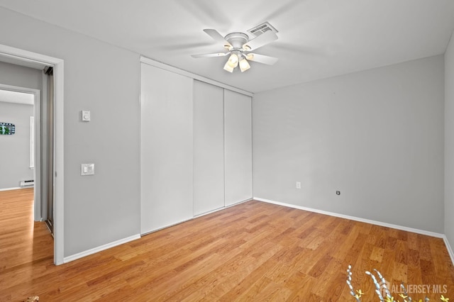 unfurnished bedroom featuring light wood finished floors, a closet, baseboards, and ceiling fan