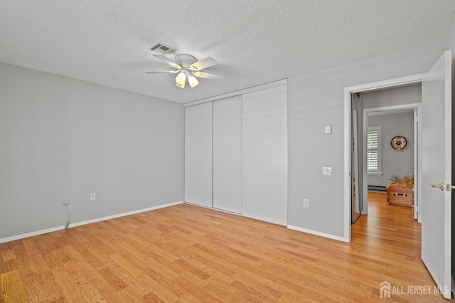 unfurnished bedroom with light wood-style flooring, a closet, a textured ceiling, ceiling fan, and baseboards