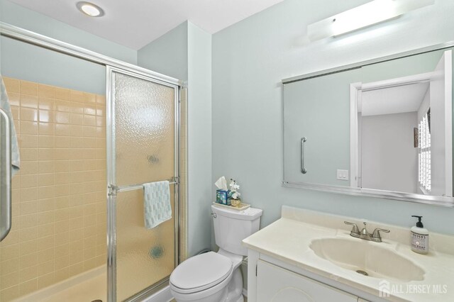 full bath featuring a stall shower, vanity, and toilet